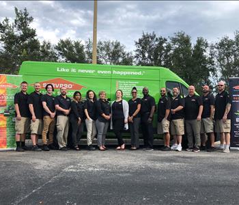 15 people standing in front of a SERVPRO van with our banners. 