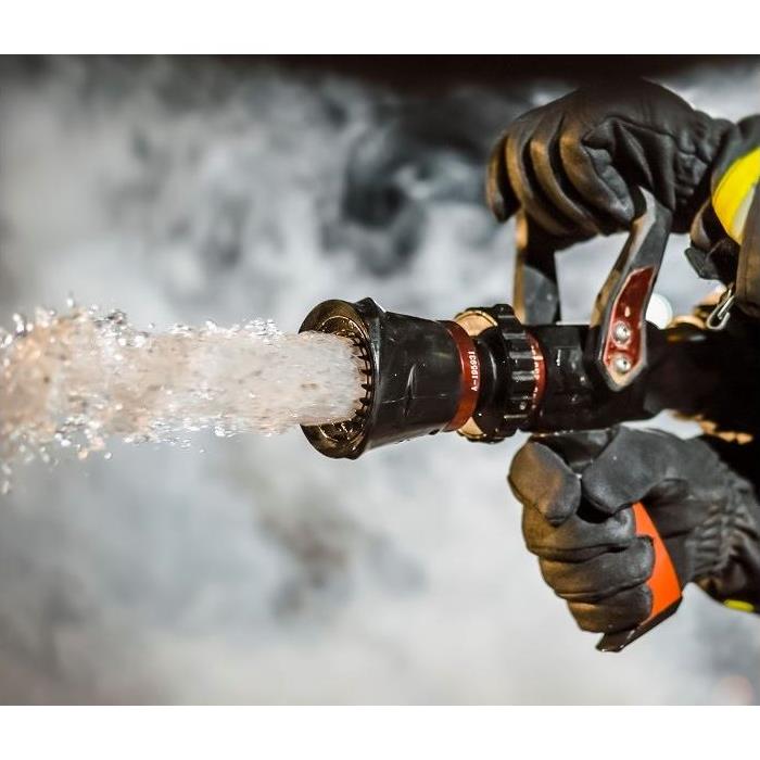 Close up of fireman holding fire hose spewing water.