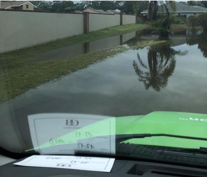 A SERVPRO vehicle sitting in front of a flooded neighborhood. 