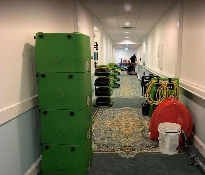 Hallway of commercial building; water damaged; SERVPRO drying equipment shown in hallway