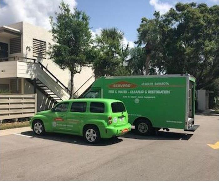 Green SERVPRO car and truck in a parking lot