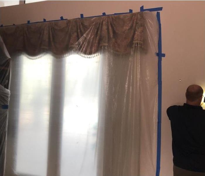 Technician installing a plastic barrier over a french door in a home