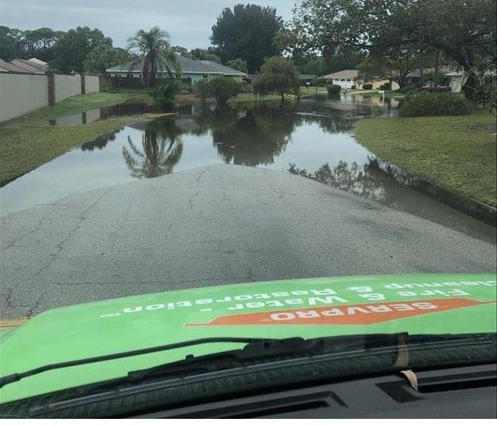 SERVPRO van driving down a street with standing water