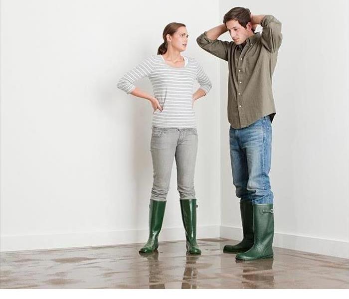 Man and Woman standing in room with water on floor