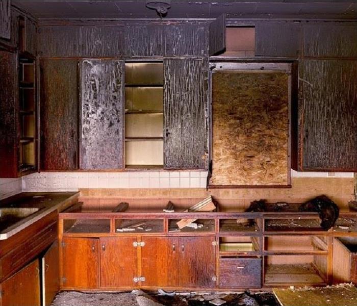 Fire damaged kitchen; charred, smoke, and soot damaged cabinets